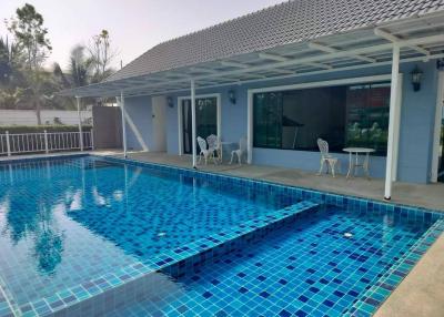Private outdoor swimming pool with patio furniture and adjacent house