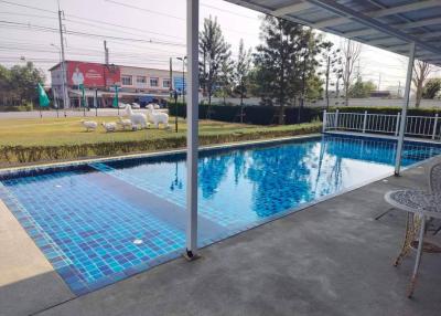 Outdoor pool with patio and seating by a residential complex