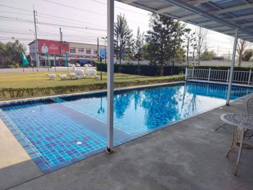 Outdoor pool with patio and seating by a residential complex
