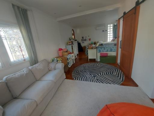 Spacious bedroom with a sectional sofa, bed, and large window