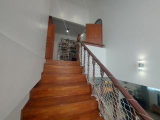 Wooden staircase leading to upper level with bookshelves and safety railings