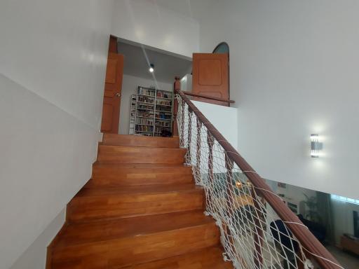 Wooden staircase leading to upper level with bookshelves and safety railings