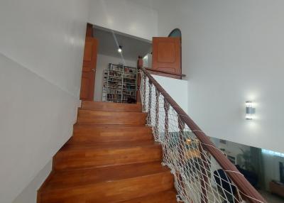 Wooden staircase leading to upper level with bookshelves and safety railings