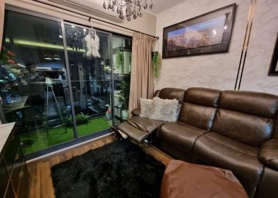 Cozy living room with leather sofa and glass sliding door leading to balcony