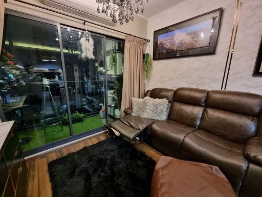 Cozy living room with leather sofa and glass sliding door leading to balcony