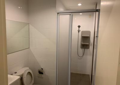 Modern clean bathroom with a shower cabin, toilet, and white tiles
