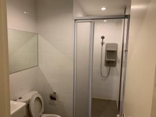 Modern clean bathroom with a shower cabin, toilet, and white tiles