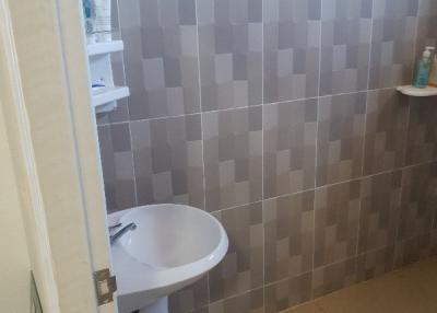 Compact bathroom with wall-mounted sink and tiled walls