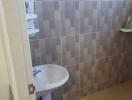 Compact bathroom with wall-mounted sink and tiled walls