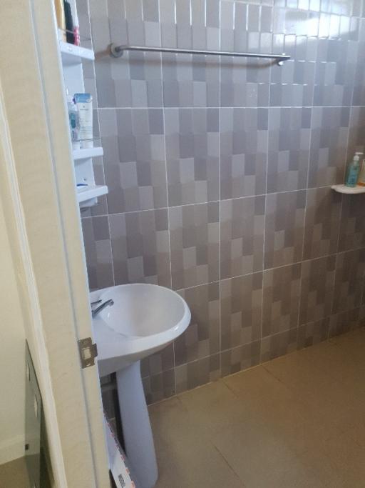 Compact bathroom with wall-mounted sink and tiled walls