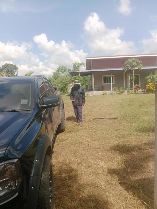 Man standing outside a house with a car parked in front