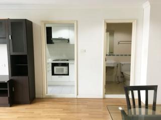 Compact apartment interior with an open doorway to the kitchen and visible entrance to the bathroom