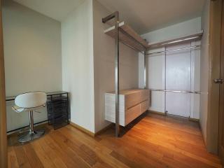 Compact bedroom with wooden flooring, loft bed, and built-in wardrobe