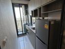 Modern compact kitchen with stainless steel appliances and balcony access