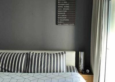 Modern bedroom with grey and blue bedding and a travel-themed wall art