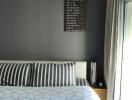 Modern bedroom with grey and blue bedding and a travel-themed wall art