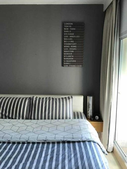 Modern bedroom with grey and blue bedding and a travel-themed wall art