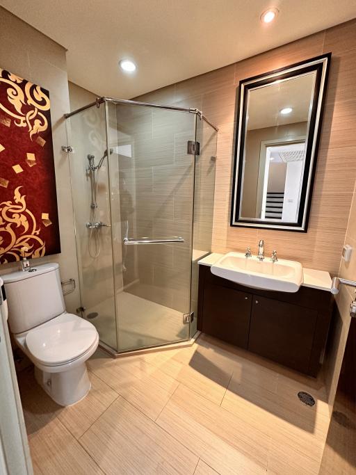 Modern bathroom with glass shower enclosure, large mirror, and dual sink vanity