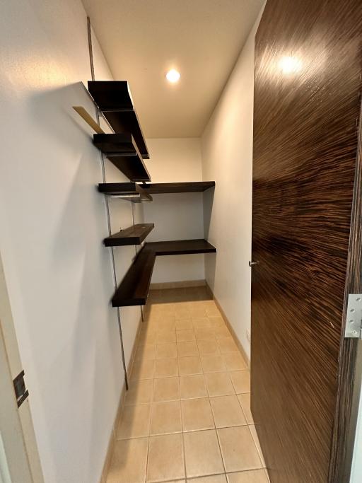 Narrow hallway with floating shelves and tiled flooring