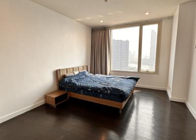Spacious bedroom with dark hardwood floors and a large window