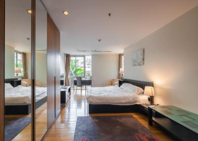 Modern bedroom interior with a large bed, mirrored wardrobe, and hardwood floors