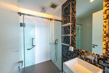 Modern bathroom with glass shower enclosure and black accent tiles