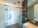 Modern bathroom with glass shower enclosure and black accent tiles