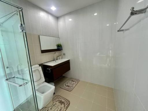 Modern bathroom with white tiles, glass shower, and wooden vanity
