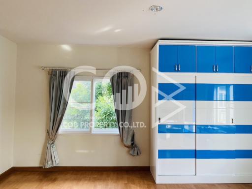 Bright bedroom with blue and white wardrobe and large window