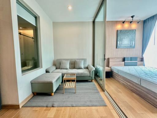 Modern bedroom with an attached bathroom, featuring a comfortable couch and a sliding glass door