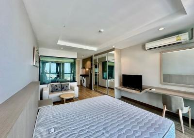 Modern bedroom with integrated living space including kitchenette, work area, and entertainment setup