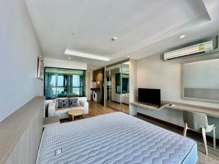 Modern bedroom with integrated living space including kitchenette, work area, and entertainment setup