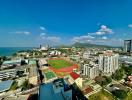 Panoramic aerial view of a coastal city with buildings, a stadium, and the sea