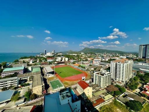 Panoramic aerial view of a coastal city with buildings, a stadium, and the sea