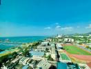 Expansive aerial view of a coastal area with urban landscape and blue sea under a clear sky