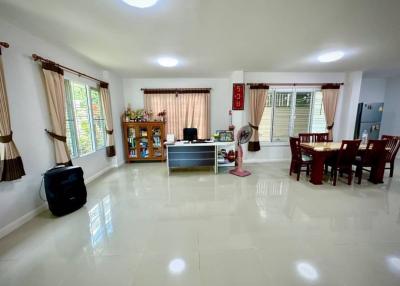 Spacious and well-lit living room with glossy tiled flooring, large windows, and modern furnishings