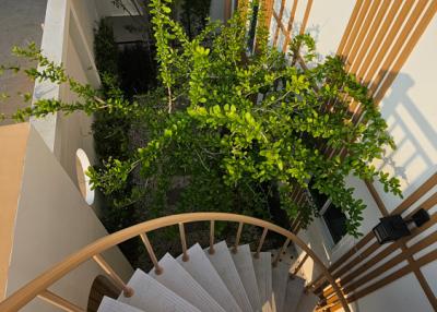 Spiral staircase with wooden accents and greenery