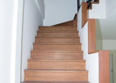 Wooden staircase with modern metal railing in a well-lit interior space