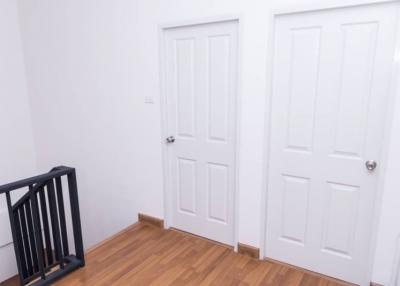Clean hallway interior with wooden flooring and two white doors