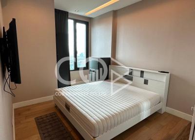 Modern bedroom with natural light and wall-mounted TV
