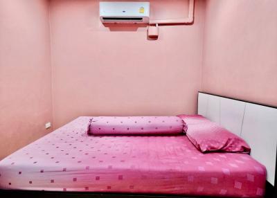 Compact bedroom with a pink theme, furnished with a large bed and air conditioning