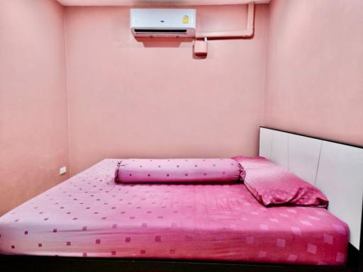Compact bedroom with a pink theme, furnished with a large bed and air conditioning