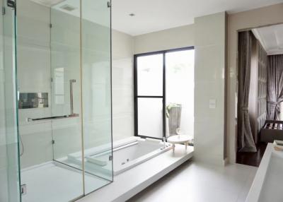 Modern bathroom with glass shower, bathtub, and natural light