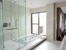 Modern bathroom with glass shower, bathtub, and natural light