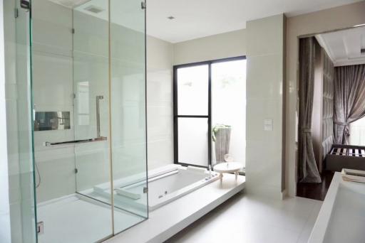 Modern bathroom with glass shower, bathtub, and natural light