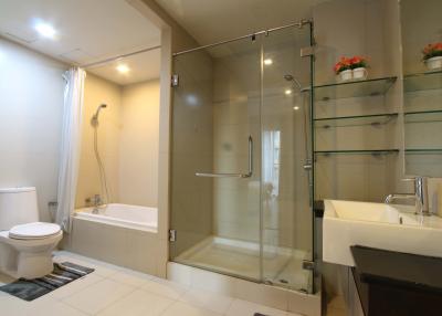 Modern bathroom with glass shower cabin, bathtub, toilet, and sink
