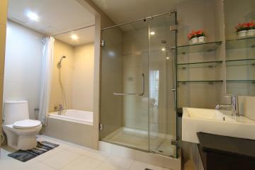 Modern bathroom with glass shower cabin, bathtub, toilet, and sink