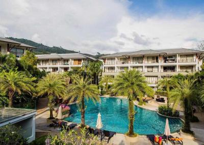 Resort-style residential building with a large swimming pool and lush greenery