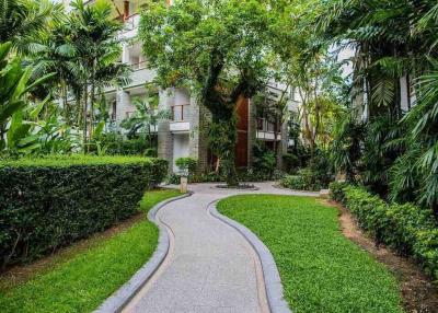 Curved pathway leading to a modern apartment building surrounded by lush greenery