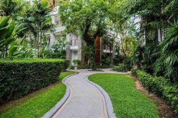 Curved pathway leading to a modern apartment building surrounded by lush greenery